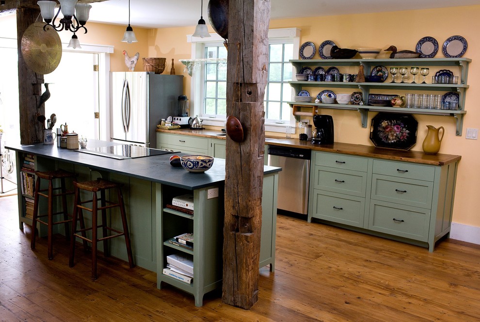 This is an example of a country galley kitchen in Boston with stainless steel appliances, open cabinets, green cabinets and wood worktops.