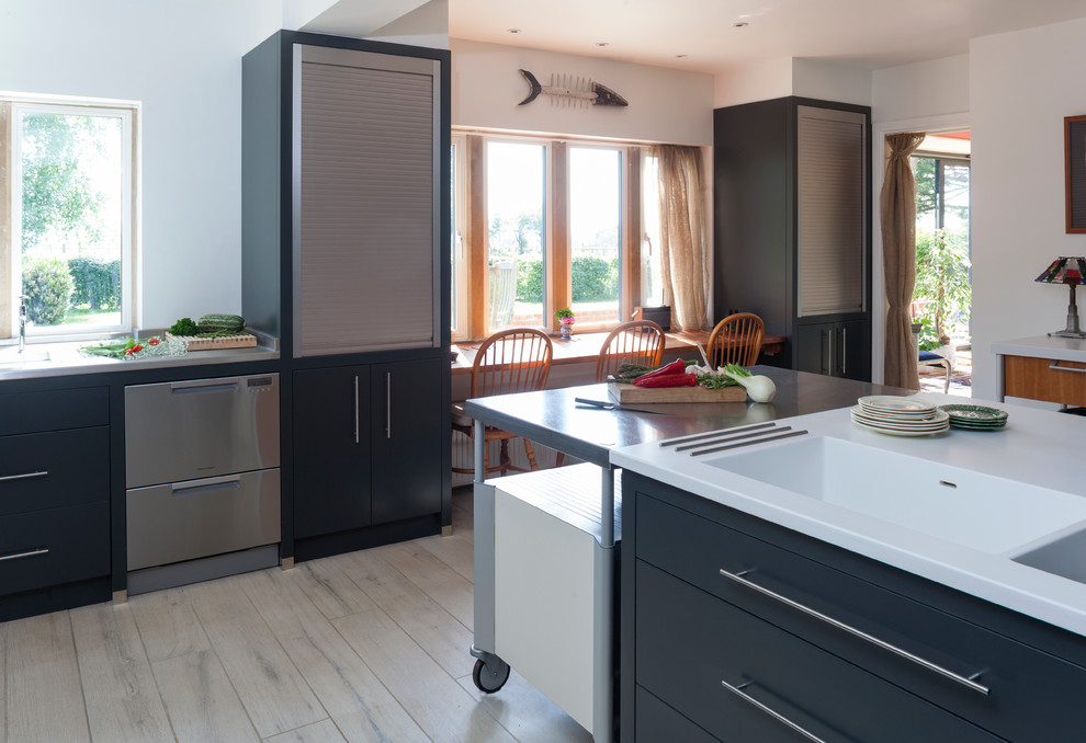 Medium sized contemporary enclosed kitchen in Wiltshire with an integrated sink, flat-panel cabinets, grey cabinets, stainless steel worktops, white splashback, porcelain splashback, stainless steel appliances and an island.