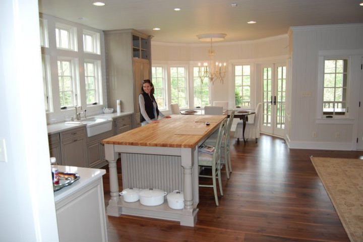 Inspiration for a mid-sized timeless l-shaped dark wood floor and brown floor open concept kitchen remodel in Huntington with a farmhouse sink, raised-panel cabinets, green cabinets, wood countertops, white backsplash, subway tile backsplash, stainless steel appliances and an island