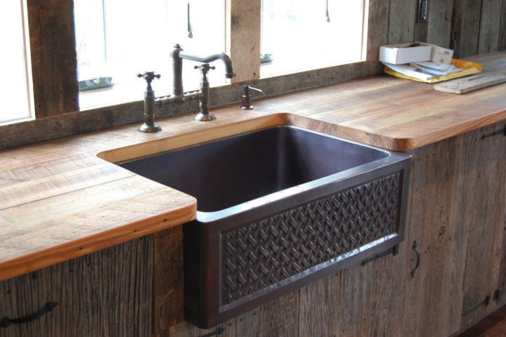 Klassisk inredning av ett mellanstort kök, med en rustik diskho, släta luckor, skåp i mörkt trä, träbänkskiva, mörkt trägolv och brunt golv