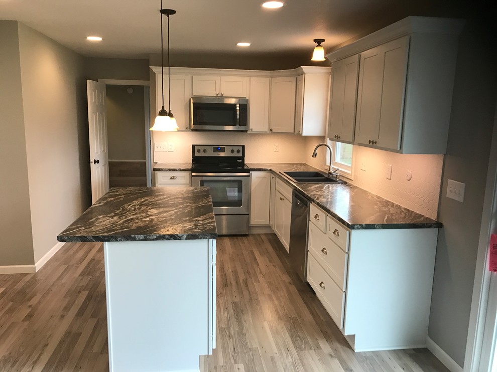 Mid-sized elegant l-shaped brown floor eat-in kitchen photo in Other with a drop-in sink, shaker cabinets, white cabinets, laminate countertops, white backsplash, stainless steel appliances and an island