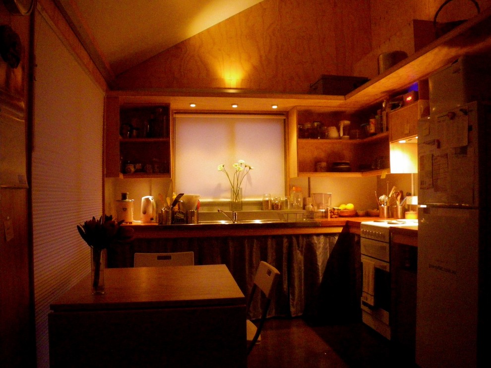Inspiration pour une petite cuisine ouverte design en L et bois clair avec un évier 2 bacs, un plan de travail en bois, une crédence métallisée, un électroménager blanc et sol en béton ciré.