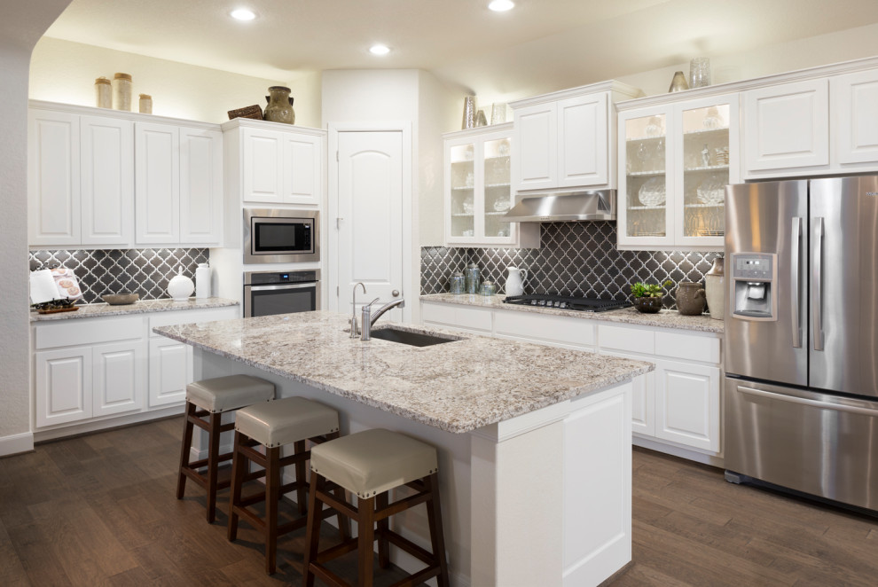 Mid-sized transitional l-shaped brown floor kitchen photo in Austin with an undermount sink, raised-panel cabinets, white cabinets, blue backsplash, porcelain backsplash, stainless steel appliances, an island and beige countertops