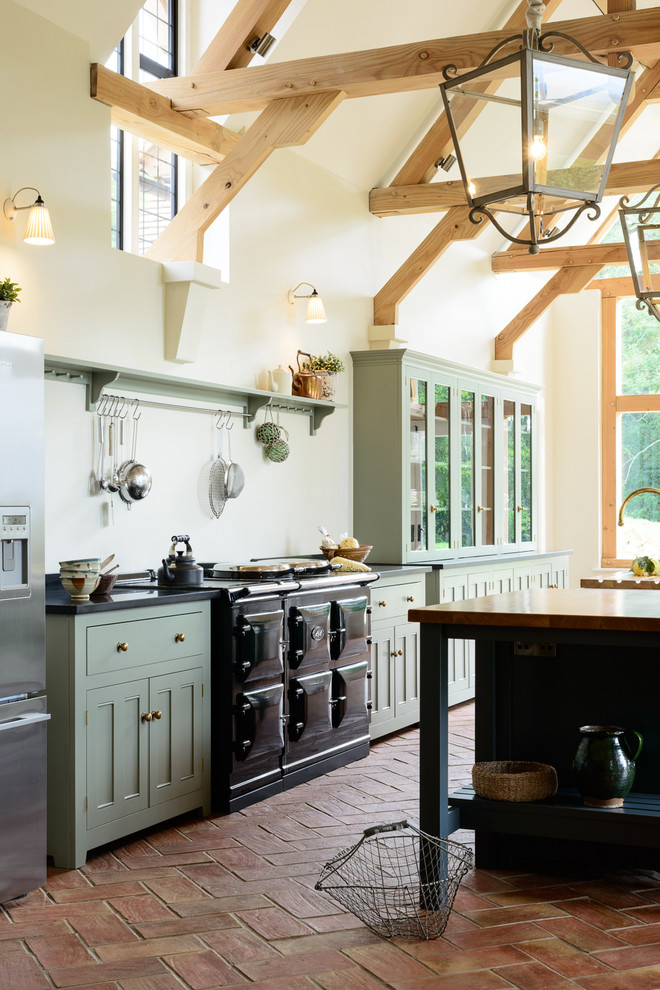 Inspiration for a large rural single-wall open plan kitchen in Other with a belfast sink, beaded cabinets, grey cabinets, granite worktops, black appliances, terracotta flooring and an island.