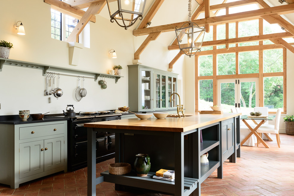Design ideas for a large rural single-wall open plan kitchen in Other with a belfast sink, beaded cabinets, grey cabinets, granite worktops, black appliances, terracotta flooring and an island.