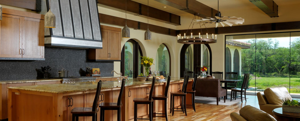 Foto på ett mycket stort amerikanskt flerfärgad kök och matrum, med en rustik diskho, luckor med infälld panel, skåp i mellenmörkt trä, granitbänkskiva, svart stänkskydd, rostfria vitvaror, mellanmörkt trägolv, flera köksöar och brunt golv