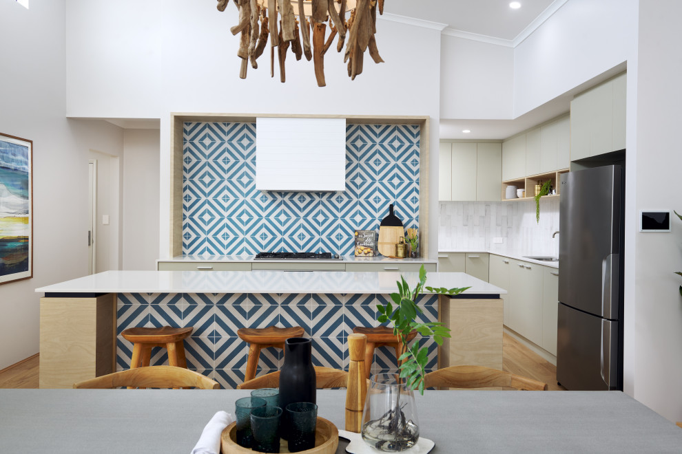 This is an example of a medium sized nautical galley open plan kitchen in Perth with a submerged sink, green cabinets, engineered stone countertops, blue splashback, ceramic splashback, stainless steel appliances, laminate floors, an island, brown floors and white worktops.