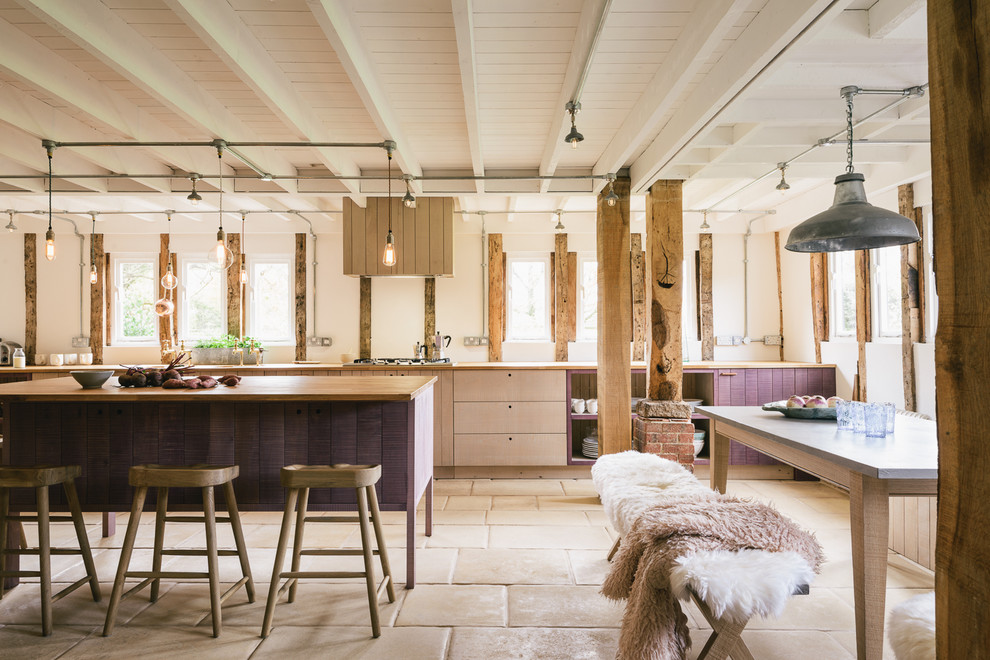 Cette photo montre une grande cuisine ouverte linéaire montagne en bois clair avec un placard à porte plane, un plan de travail en bois et îlot.