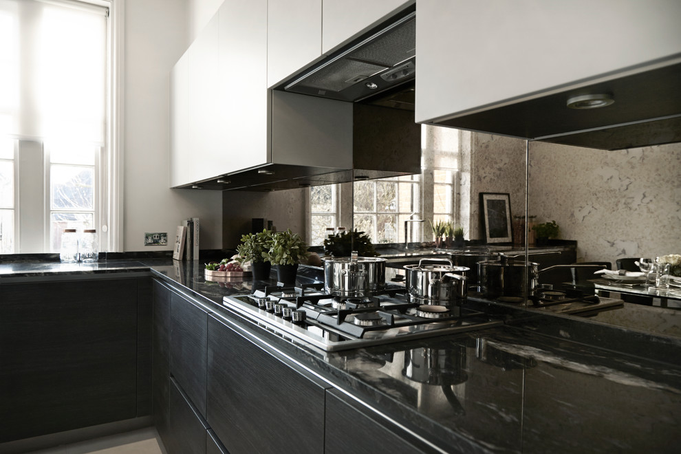 ロンドンにあるコンテンポラリースタイルのおしゃれなキッチン (アンダーカウンターシンク、フラットパネル扉のキャビネット、ミラータイルのキッチンパネル、パネルと同色の調理設備、磁器タイルの床) の写真