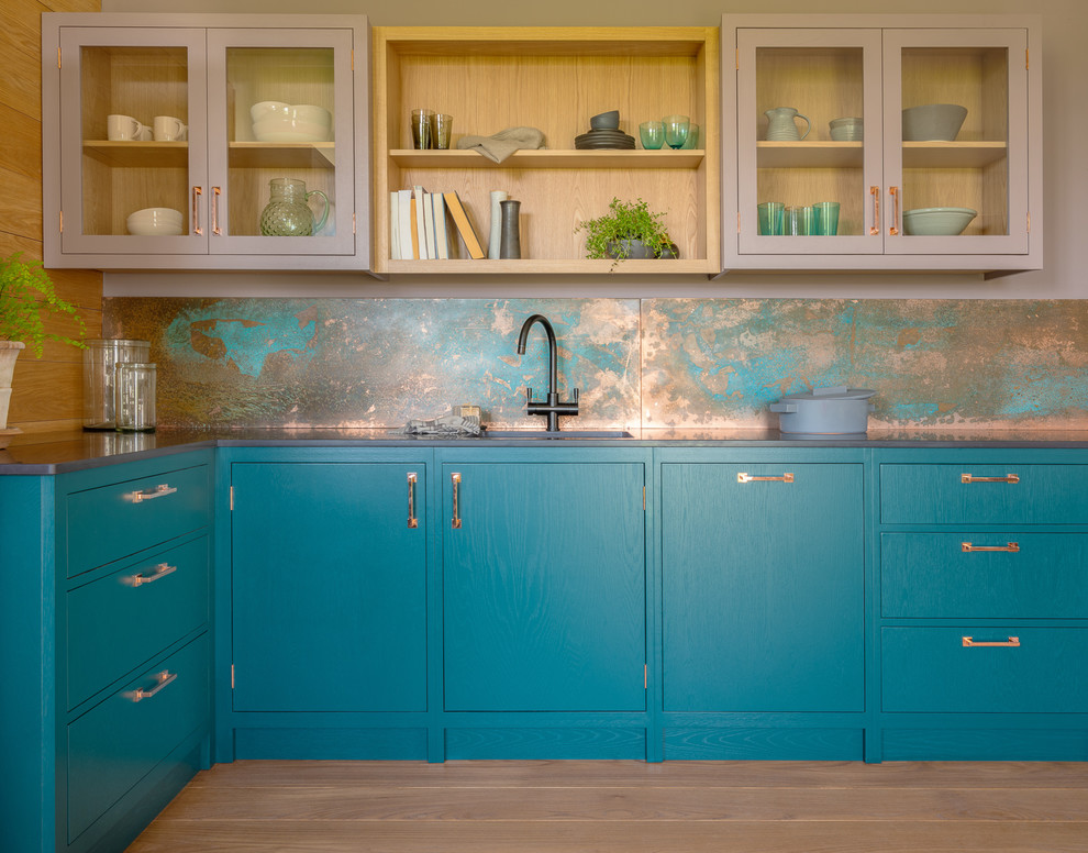 Small trendy l-shaped medium tone wood floor and brown floor open concept kitchen photo in Other with a single-bowl sink, flat-panel cabinets, quartz countertops, an island, black countertops, blue cabinets and metallic backsplash