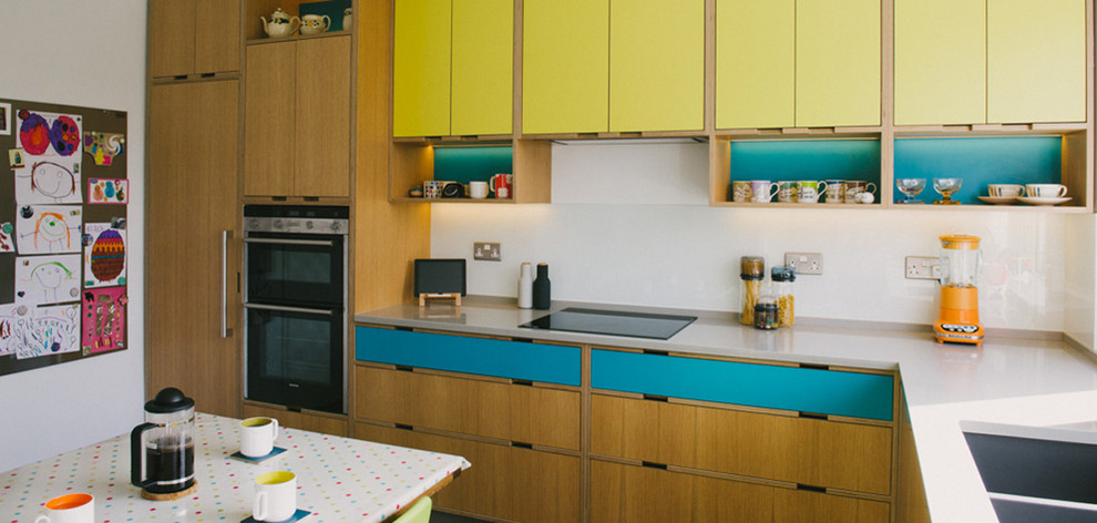 Foto på ett mellanstort retro kök, med en nedsänkt diskho, släta luckor, gula skåp, bänkskiva i kvartsit, gult stänkskydd, stänkskydd i glaskakel, rostfria vitvaror och betonggolv