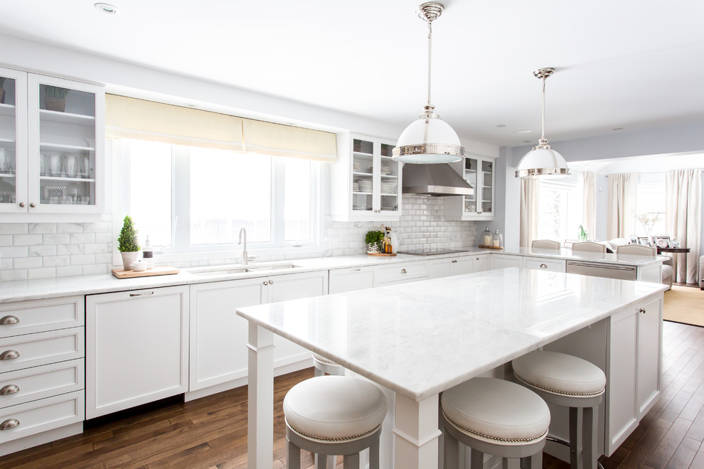 Large trendy l-shaped dark wood floor and brown floor eat-in kitchen photo in Montreal with an undermount sink, recessed-panel cabinets, white cabinets, marble countertops, gray backsplash, subway tile backsplash, white appliances and an island