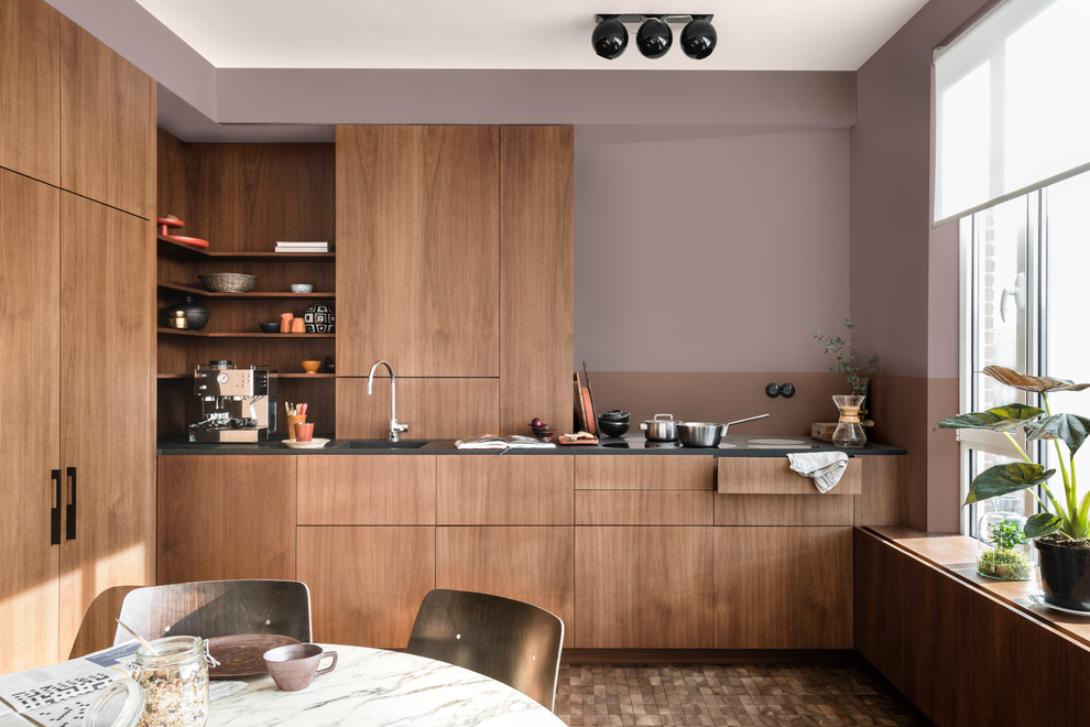 Contemporary l-shaped kitchen/diner in Berkshire with an integrated sink, flat-panel cabinets, dark wood cabinets, integrated appliances and a feature wall.