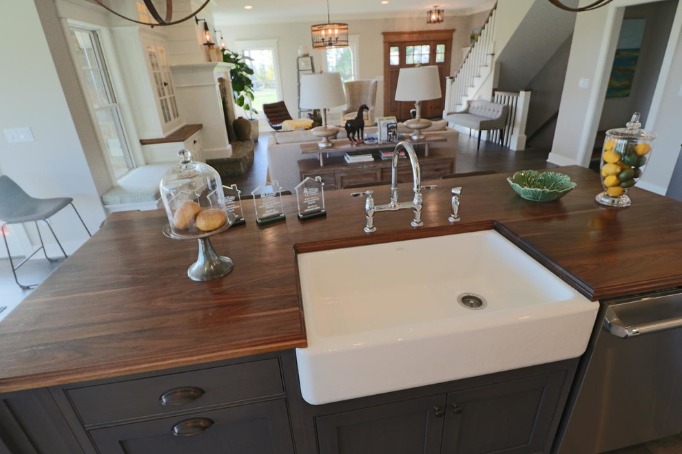 Example of a mid-sized farmhouse l-shaped dark wood floor eat-in kitchen design in Boston with a farmhouse sink, beaded inset cabinets, white cabinets, wood countertops, white backsplash, subway tile backsplash, stainless steel appliances and an island