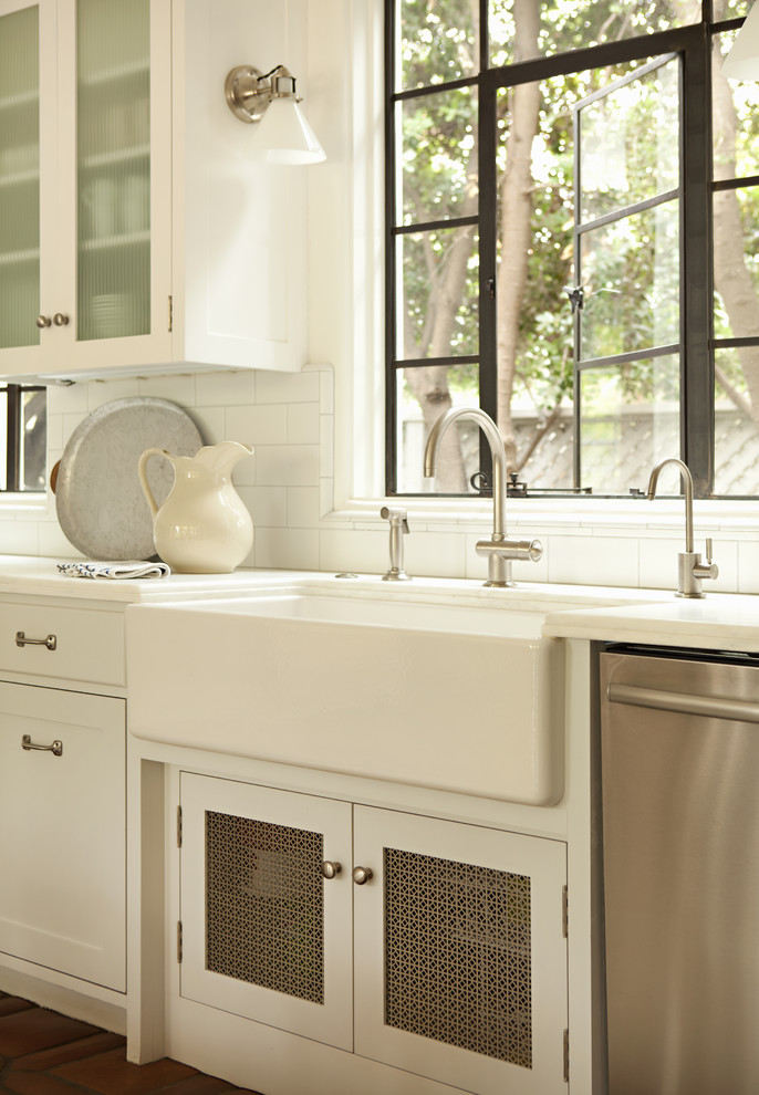 Elegant kitchen photo in Los Angeles with glass-front cabinets, subway tile backsplash and a farmhouse sink