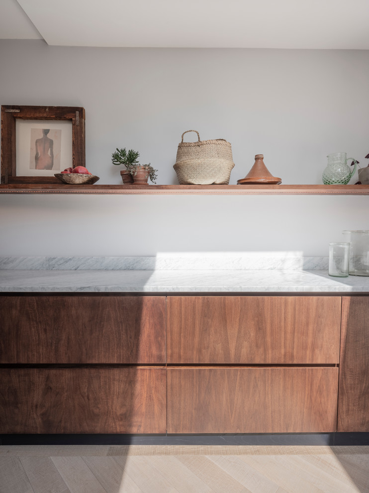 Photo of a large contemporary single-wall open plan kitchen in London with an integrated sink, flat-panel cabinets, dark wood cabinets, marble worktops, stainless steel appliances, medium hardwood flooring, an island and white worktops.