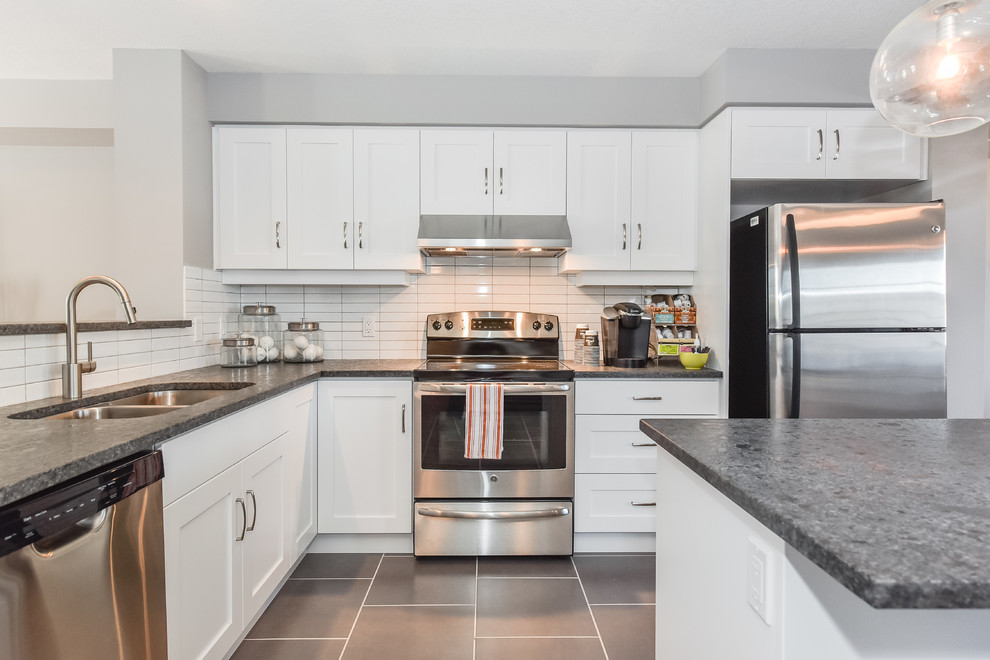This is an example of a medium sized classic l-shaped open plan kitchen in Toronto with a submerged sink, shaker cabinets, white cabinets, granite worktops, white splashback, ceramic splashback, stainless steel appliances, porcelain flooring and an island.