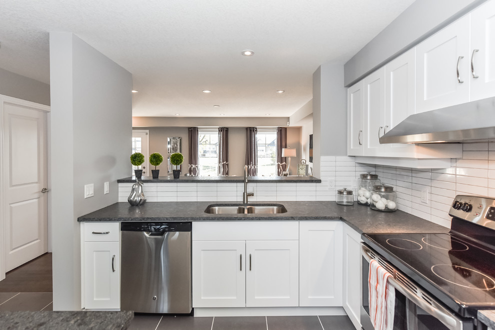 Mid-sized transitional l-shaped ceramic tile eat-in kitchen photo in Toronto with an undermount sink, shaker cabinets, white cabinets, granite countertops, white backsplash, ceramic backsplash, stainless steel appliances and an island