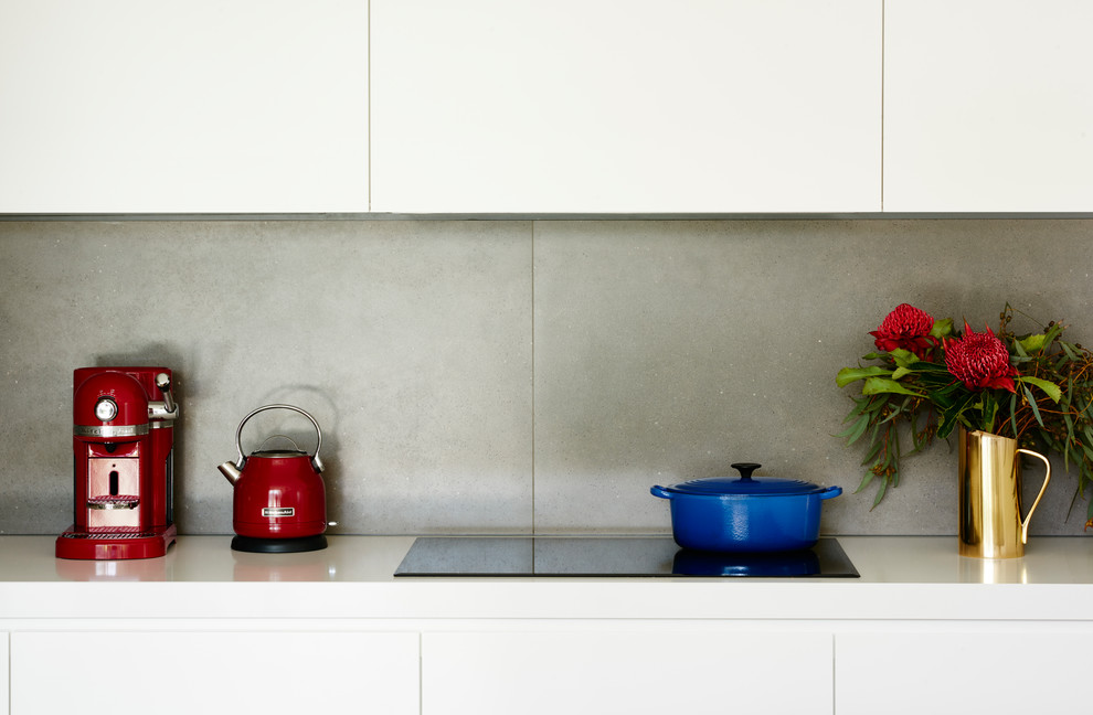 Exempel på ett modernt kök, med en undermonterad diskho, släta luckor, vita skåp, grått stänkskydd, stänkskydd i cementkakel, rostfria vitvaror, mellanmörkt trägolv, en köksö och brunt golv