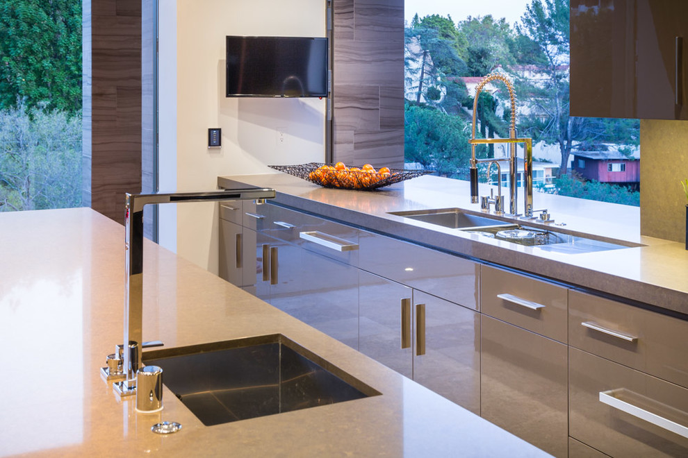 Foto på ett mellanstort funkis kök, med en integrerad diskho, släta luckor, grå skåp, grått stänkskydd, stänkskydd i sten, rostfria vitvaror, marmorgolv och en köksö