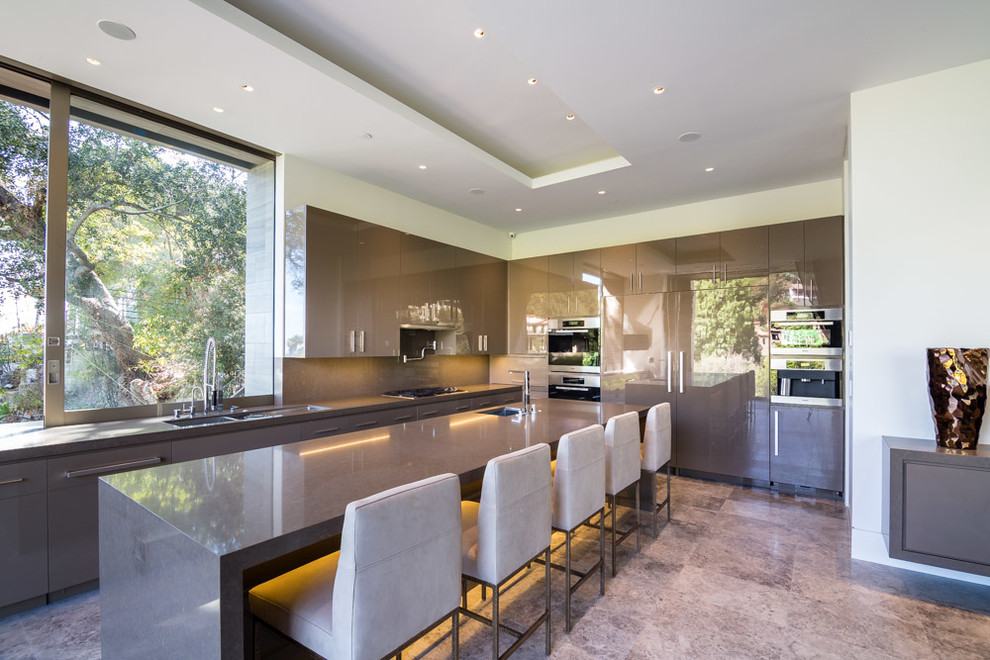 Moderne Küche mit flächenbündigen Schrankfronten, grauen Schränken, Küchenrückwand in Grau, Kücheninsel und Elektrogeräten mit Frontblende in Los Angeles