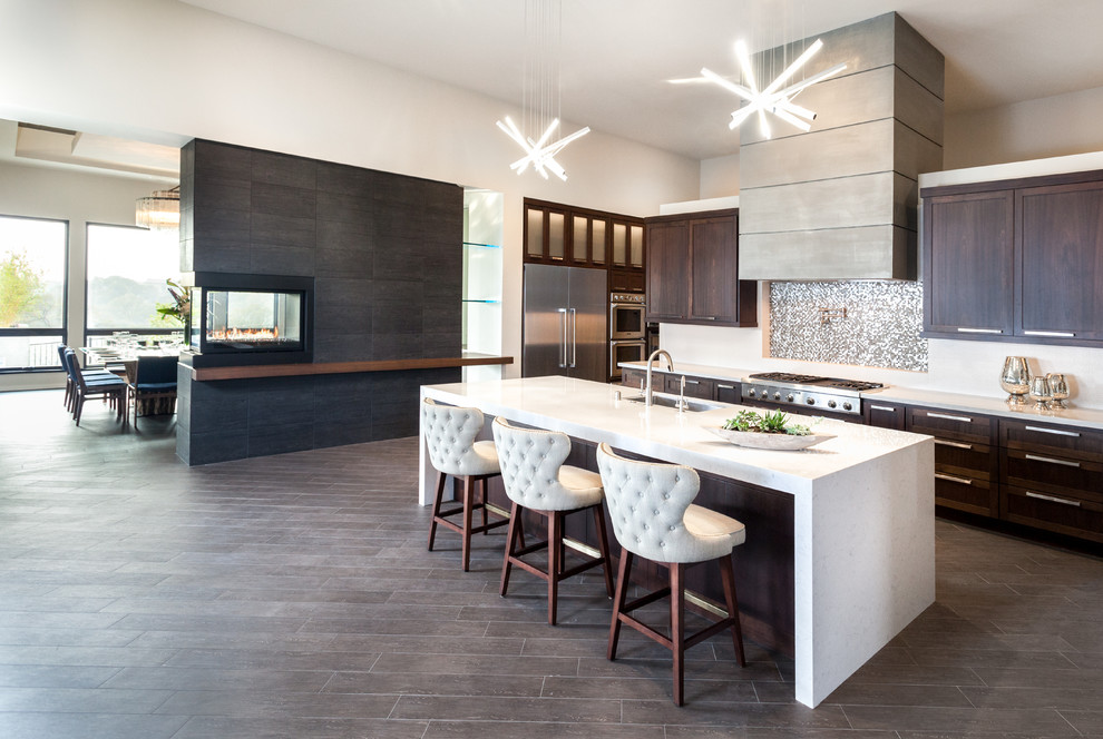 Inspiration for a huge contemporary single-wall porcelain tile and brown floor eat-in kitchen remodel in Los Angeles with an undermount sink, shaker cabinets, dark wood cabinets, metallic backsplash, mosaic tile backsplash, stainless steel appliances, an island and solid surface countertops