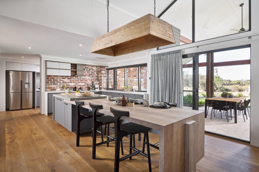 Moderne Küche in L-Form mit flächenbündigen Schrankfronten, grauen Schränken, Küchenrückwand in Rot, Rückwand aus Backstein, braunem Holzboden, Kücheninsel, braunem Boden und grauer Arbeitsplatte in Perth