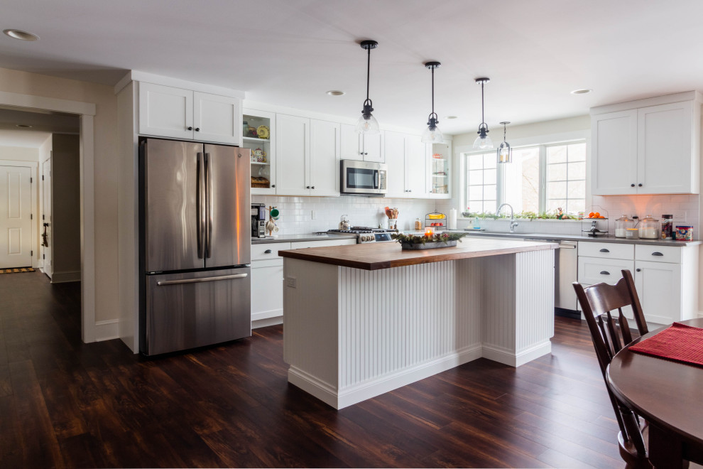 Inspiration for a large country l-shaped vinyl floor and brown floor eat-in kitchen remodel in Other with an undermount sink, shaker cabinets, white cabinets, quartzite countertops, white backsplash, ceramic backsplash, stainless steel appliances, an island and gray countertops