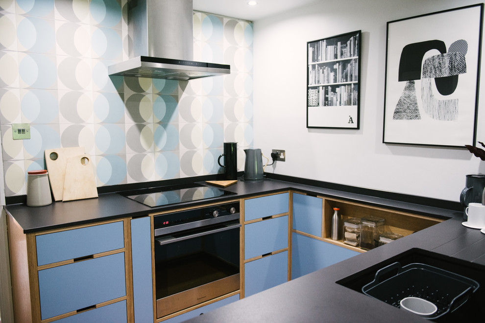 Photo of a small midcentury u-shaped kitchen in Other with flat-panel cabinets, blue cabinets, no island, black worktops, an integrated sink, blue splashback and black appliances.