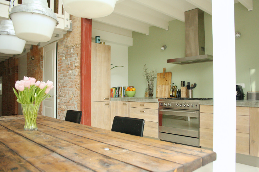 Ejemplo de cocina comedor urbana con armarios con paneles lisos, puertas de armario de madera clara y electrodomésticos de acero inoxidable