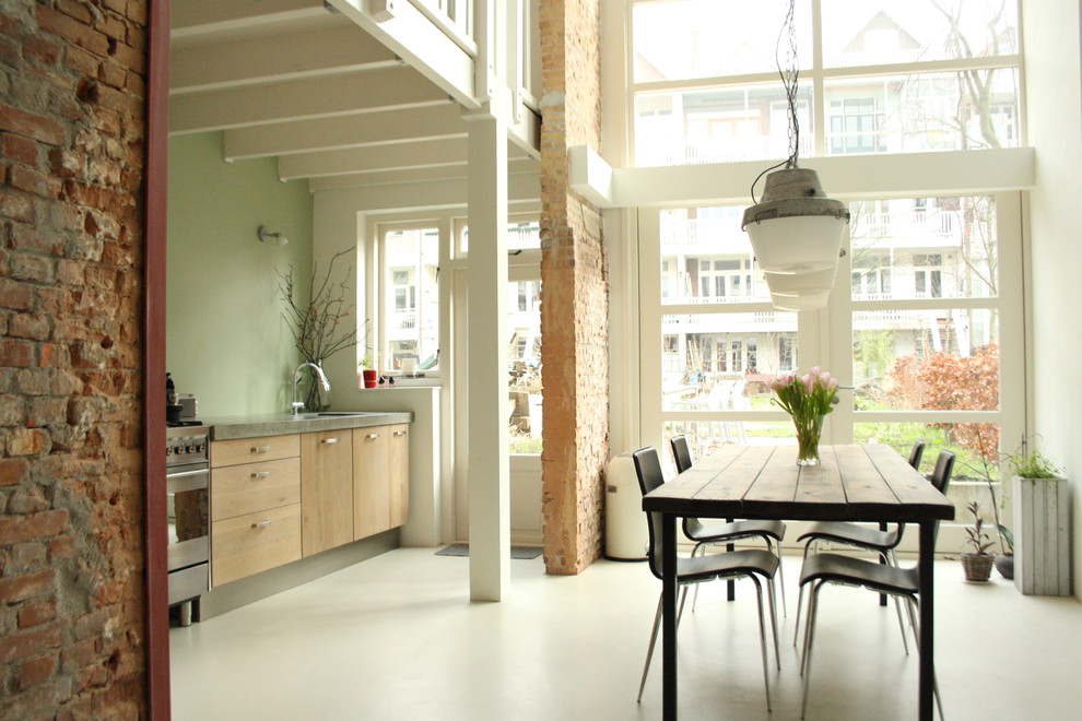 Inspiration for an industrial kitchen/diner in Amsterdam with flat-panel cabinets, light wood cabinets and stainless steel appliances.