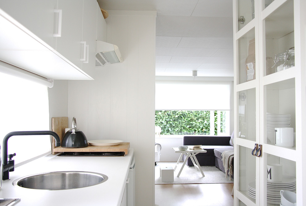 Diseño de cocina nórdica cerrada con fregadero encastrado, armarios con paneles lisos, puertas de armario blancas y electrodomésticos blancos