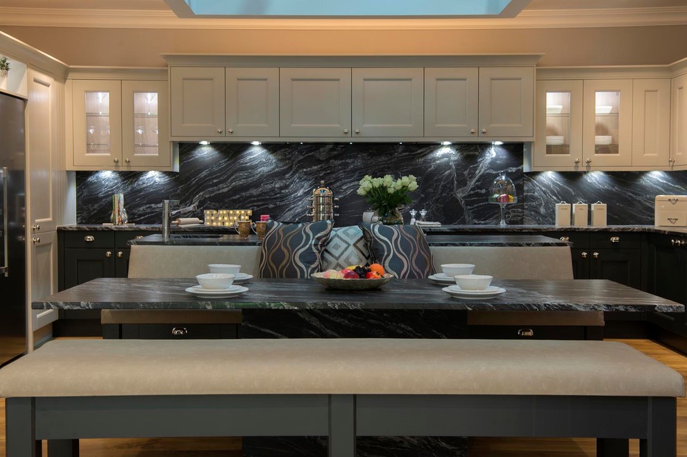 Foto på ett stort funkis svart kök, med en integrerad diskho, skåp i shakerstil, grå skåp, granitbänkskiva, svart stänkskydd, stänkskydd i sten, svarta vitvaror, ljust trägolv, en köksö och brunt golv