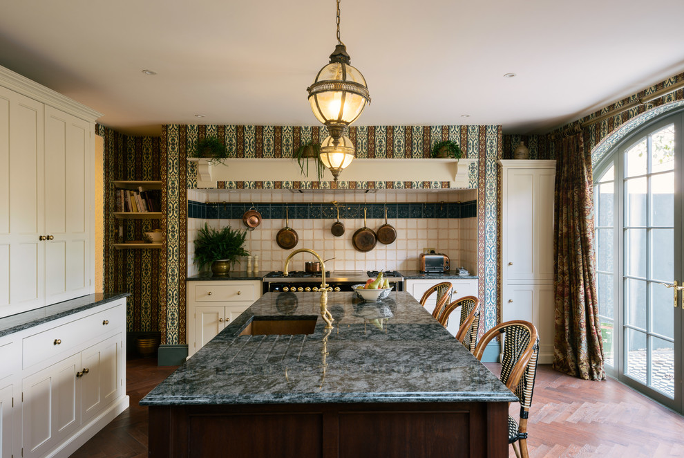 Foto di un cucina con isola centrale tradizionale di medie dimensioni con lavello sottopiano, ante con riquadro incassato, ante beige, top in granito, parquet scuro, pavimento blu e top grigio