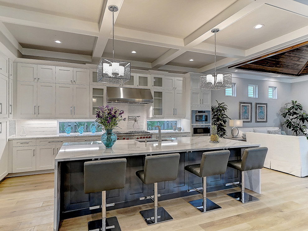 Eat-in kitchen - large transitional l-shaped light wood floor eat-in kitchen idea in Tampa with an undermount sink, shaker cabinets, white cabinets, quartzite countertops, white backsplash, porcelain backsplash, paneled appliances and an island