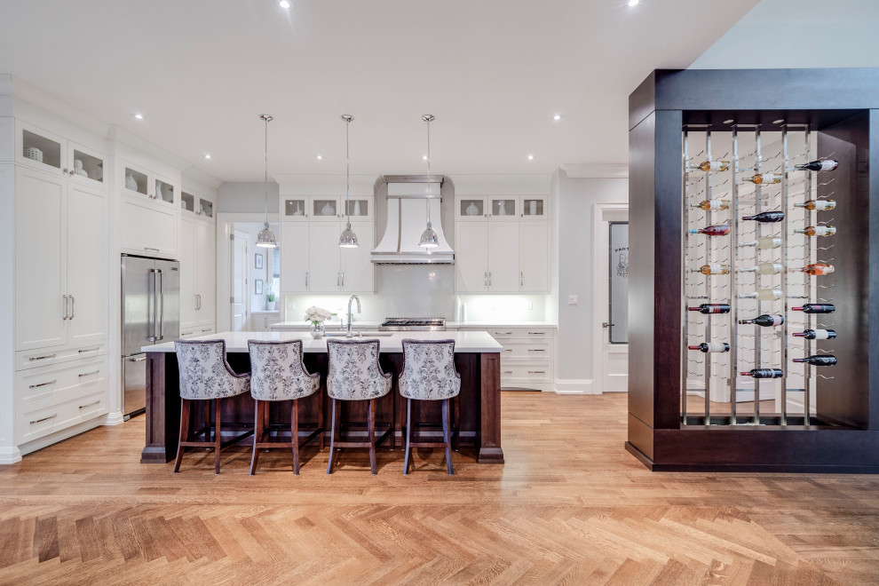 Traditional kitchen in Toronto with a double-bowl sink, white cabinets, white splashback, stainless steel appliances, medium hardwood flooring, brown floors and white worktops.