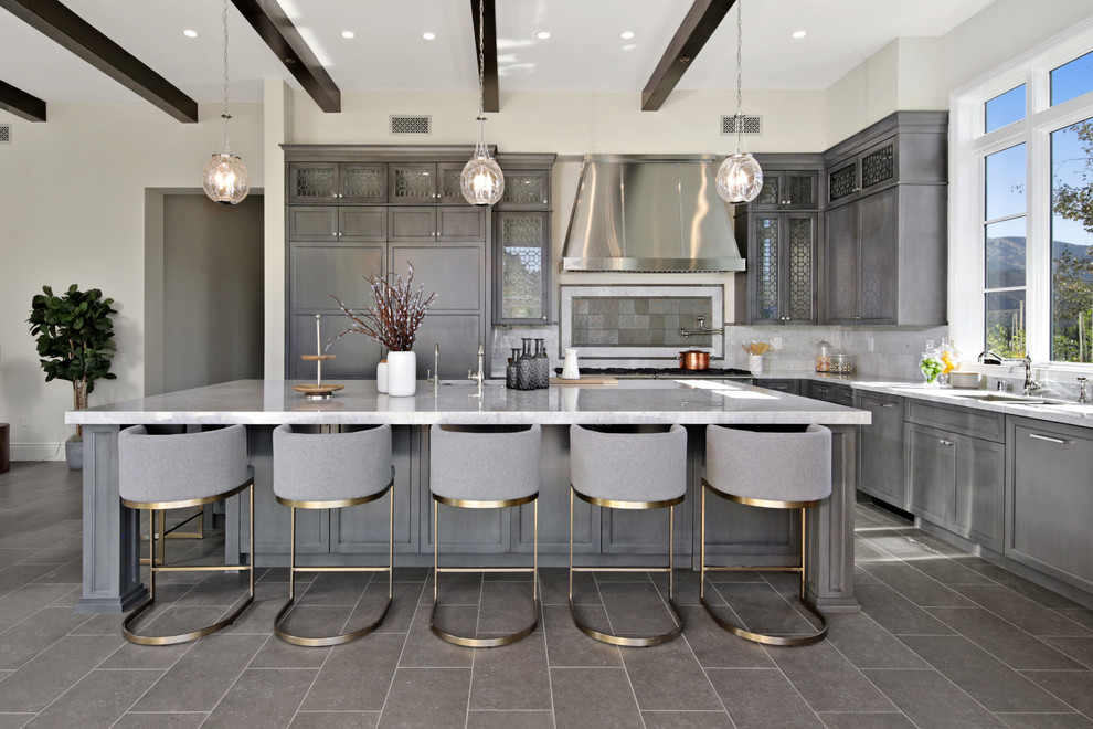 Inredning av ett medelhavsstil l-kök, med en dubbel diskho, luckor med infälld panel, grå skåp, grått stänkskydd, en köksö, grått golv och marmorbänkskiva