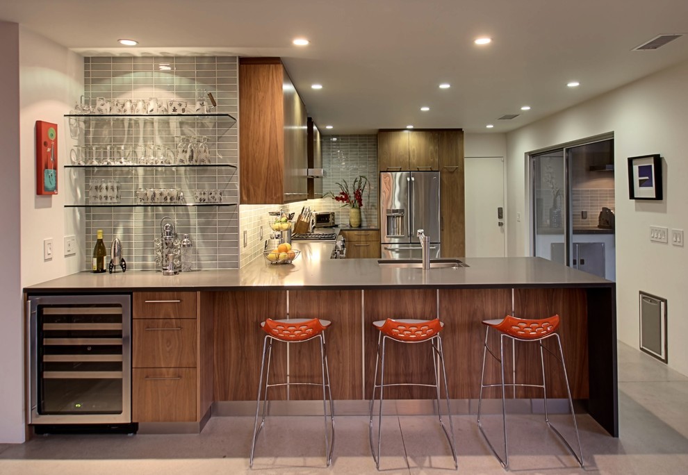 Eat-in kitchen - 1950s l-shaped concrete floor eat-in kitchen idea in Other with flat-panel cabinets, medium tone wood cabinets, gray backsplash, subway tile backsplash, stainless steel appliances and a peninsula