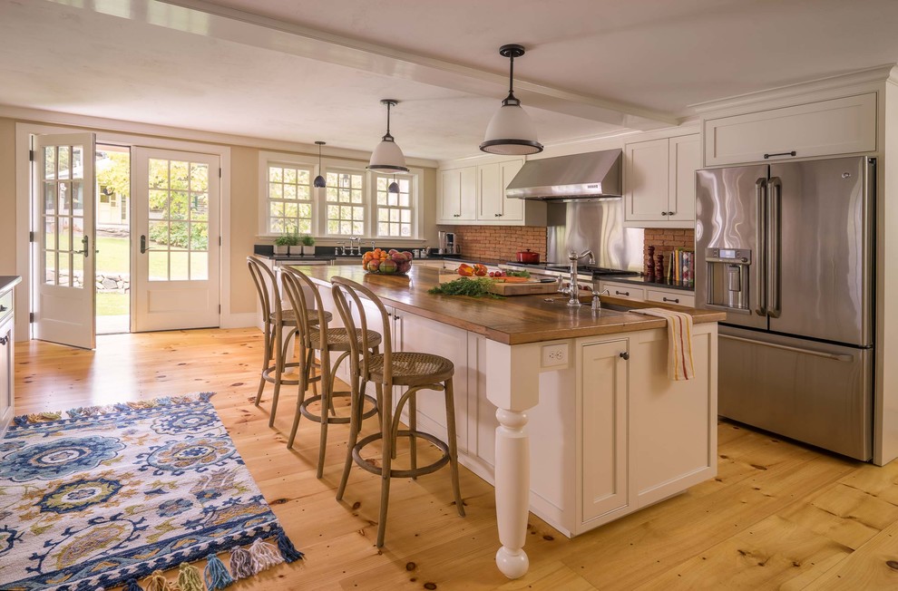 Foto på ett lantligt kök med öppen planlösning, med en rustik diskho, luckor med infälld panel, vita skåp, granitbänkskiva, rostfria vitvaror, ljust trägolv och flera köksöar