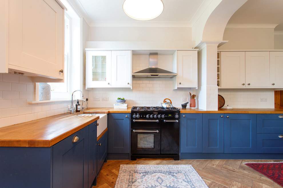 Cette image montre une cuisine traditionnelle avec un placard à porte shaker, un plan de travail en bois, une crédence blanche, une crédence en céramique, un sol marron et un plan de travail marron.