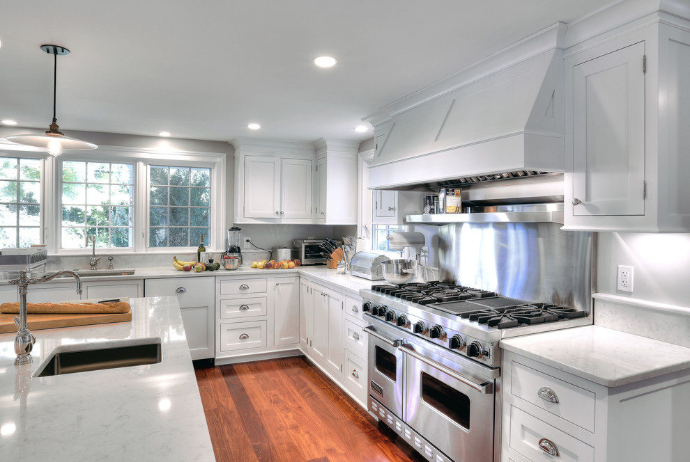 Example of a large country u-shaped medium tone wood floor eat-in kitchen design in New York with an undermount sink, recessed-panel cabinets, white cabinets, marble countertops, white backsplash, stone slab backsplash, paneled appliances and an island