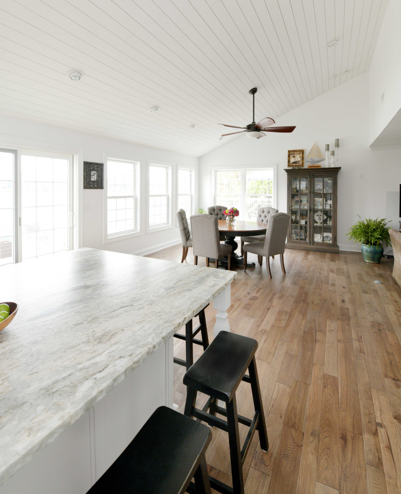 Inredning av ett lantligt stort grå grått kök, med en undermonterad diskho, luckor med infälld panel, vita skåp, granitbänkskiva, grått stänkskydd, stänkskydd i tegel, integrerade vitvaror, mellanmörkt trägolv, en köksö och brunt golv