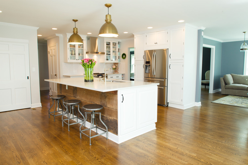 Eat-in kitchen - large cottage u-shaped medium tone wood floor and brown floor eat-in kitchen idea in Columbus with a drop-in sink, white cabinets, quartz countertops, white backsplash, subway tile backsplash, stainless steel appliances, an island and flat-panel cabinets