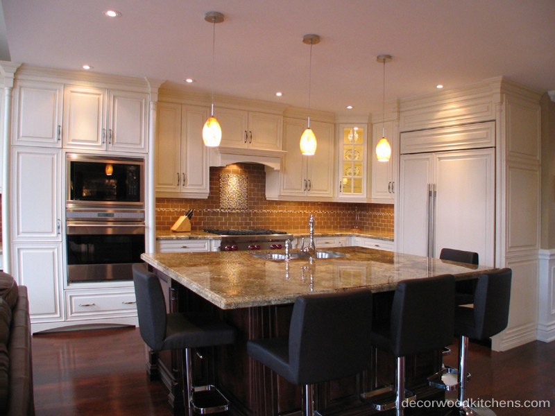 This is an example of a large traditional l-shaped kitchen/diner in Toronto with a submerged sink, raised-panel cabinets, white cabinets, granite worktops, beige splashback, glass tiled splashback, stainless steel appliances and dark hardwood flooring.