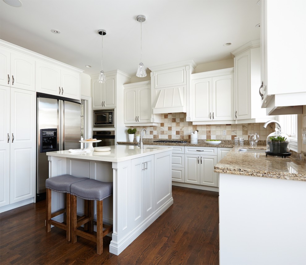 Inspiration for a timeless u-shaped kitchen remodel in Toronto with an undermount sink, raised-panel cabinets, white cabinets, granite countertops, beige backsplash, stone tile backsplash and stainless steel appliances