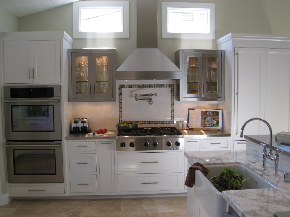 Cette image montre une cuisine design en inox avec un placard à porte vitrée.