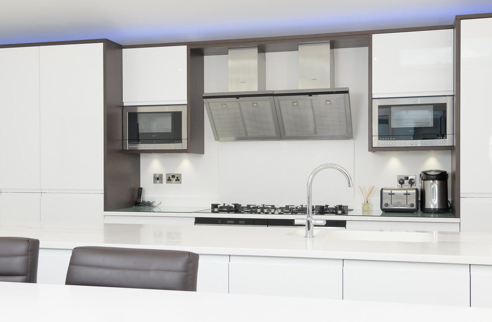 Photo of a large contemporary kitchen in Other with an integrated sink, white cabinets, composite countertops, white splashback and integrated appliances.