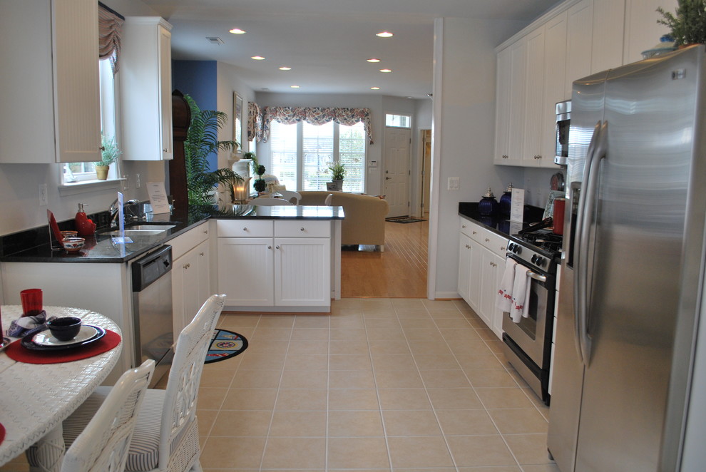 Beach style u-shaped kitchen photo in Other with white cabinets, granite countertops and stainless steel appliances