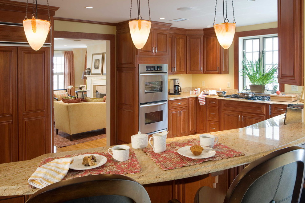Moderne Küche mit Küchengeräten aus Edelstahl, profilierten Schrankfronten, hellbraunen Holzschränken und Granit-Arbeitsplatte in Boston