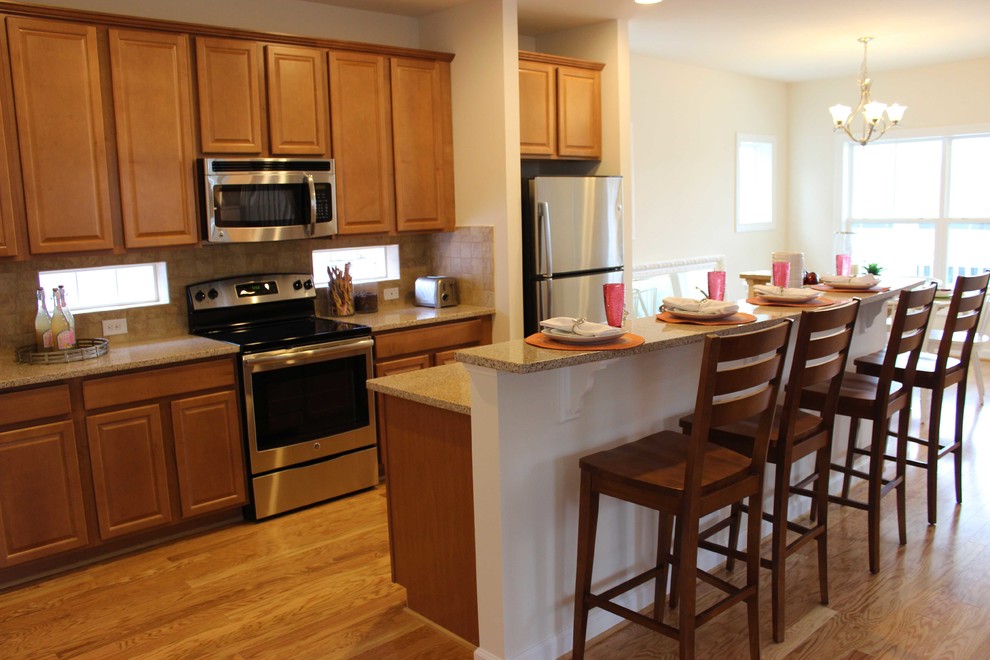 Foto di una cucina costiera con ante in legno chiaro, top in granito, paraspruzzi beige, elettrodomestici in acciaio inossidabile e parquet chiaro